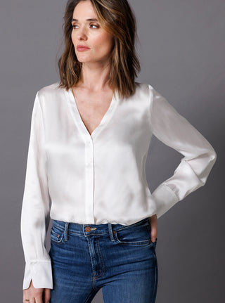 Pale grey silk blouse with button front. Y-collar neckline with small ruffle trim around neck band. Elastic sleeve cuff finish with ruffle.