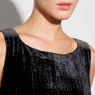 Close-up of a person wearing a black textured velvet dress with a neutral background
