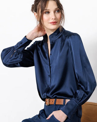 Woman wearing a blue satin shirt with a plain background